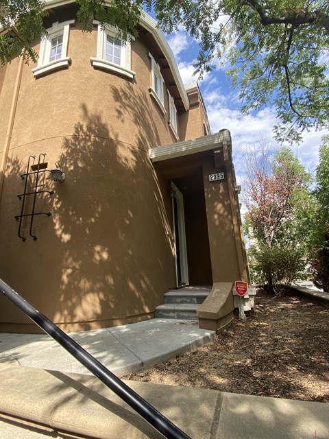 A house with a brown stucco exterior and a black iron fence.