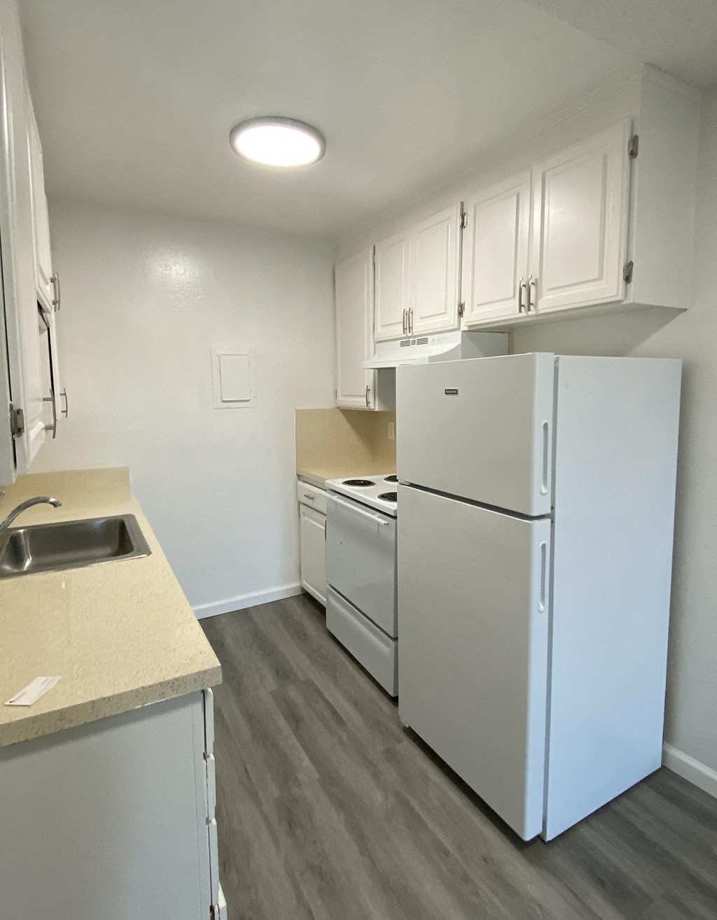 an empty kitchen with white appliances and white cabinets