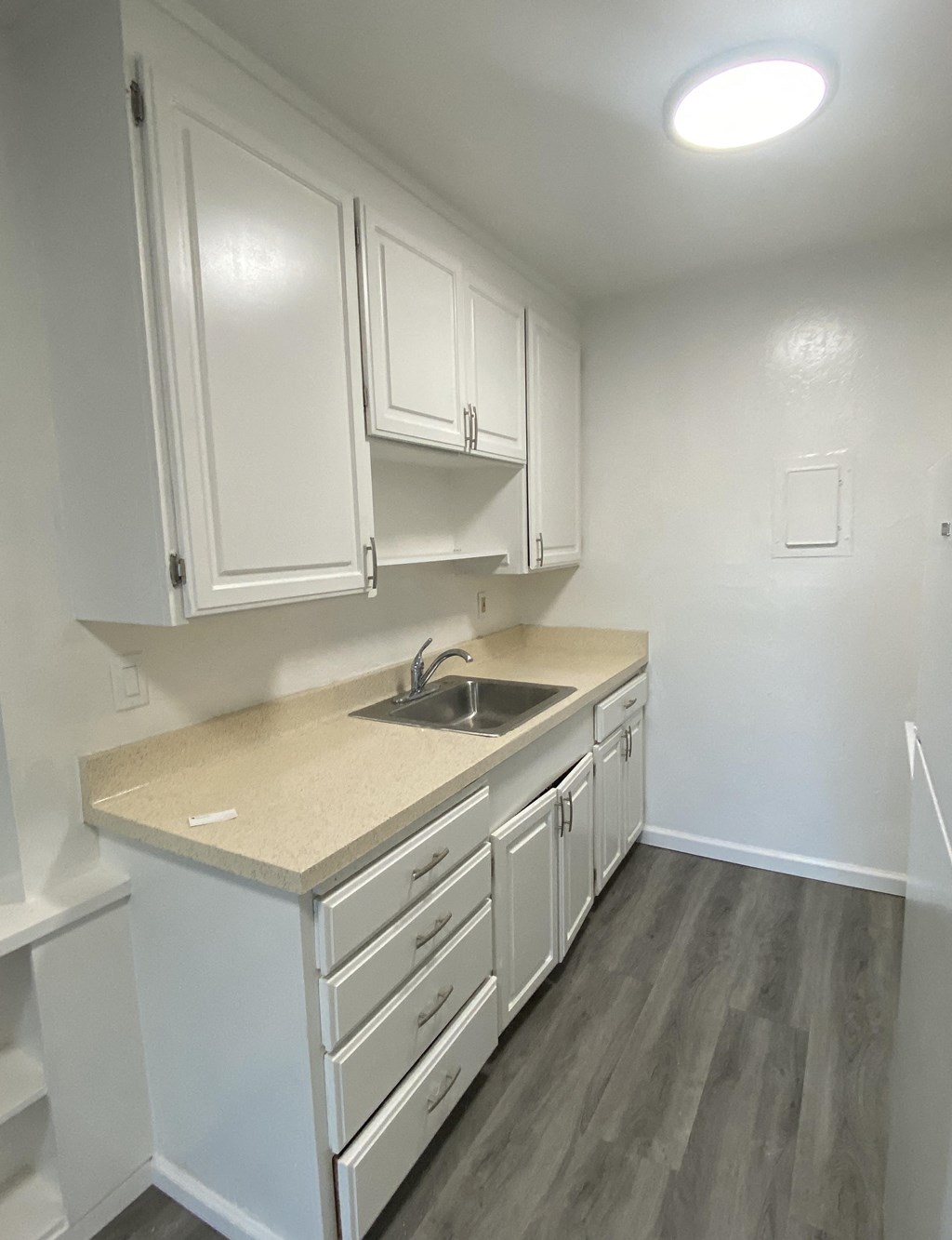an empty kitchen with white cabinets and a sink