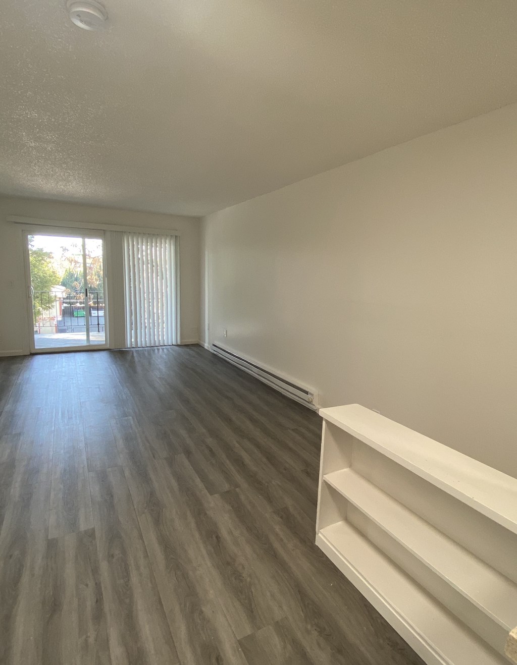 an empty living room with wood flooring and a sliding glass door