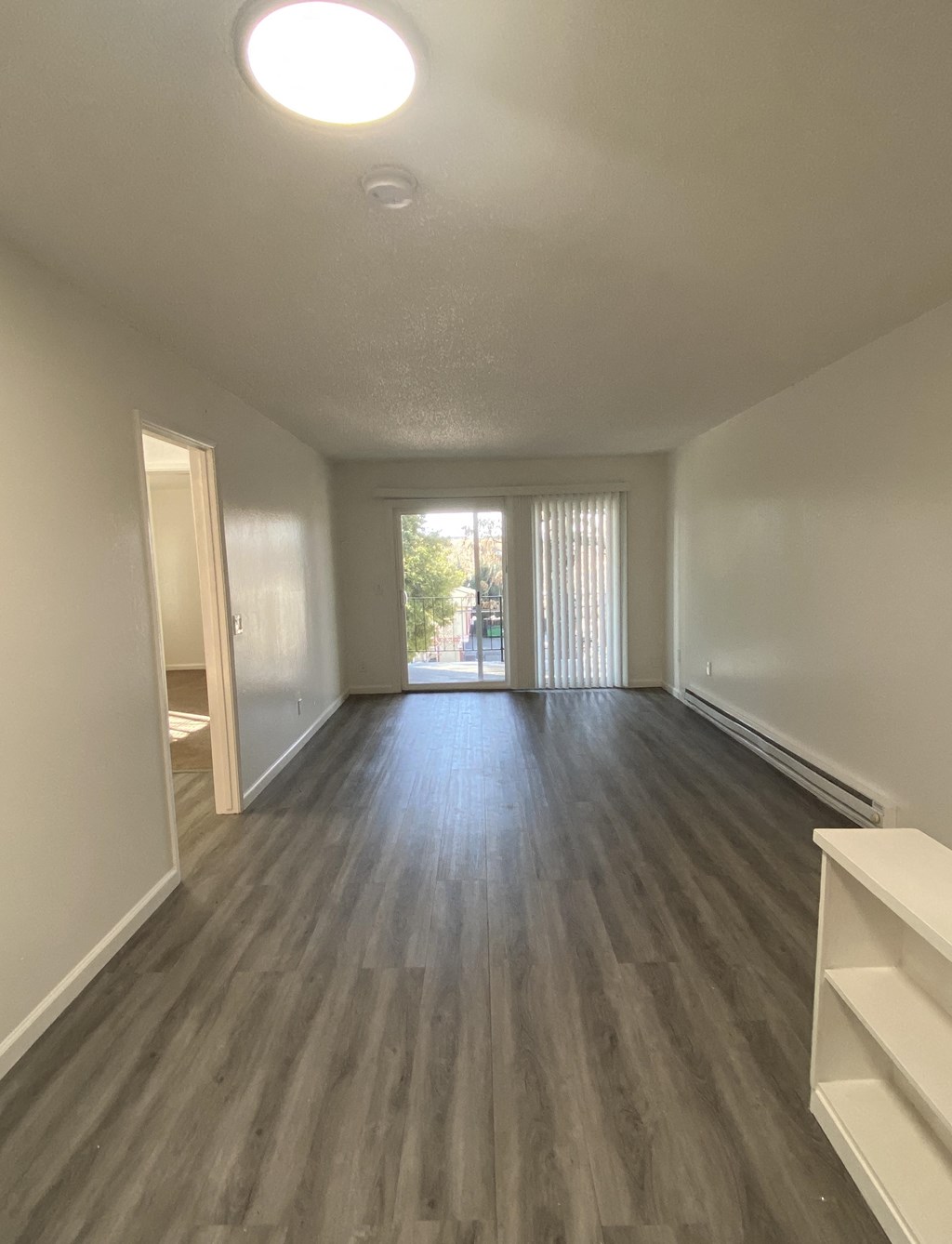 an empty living room with wood flooring and a window