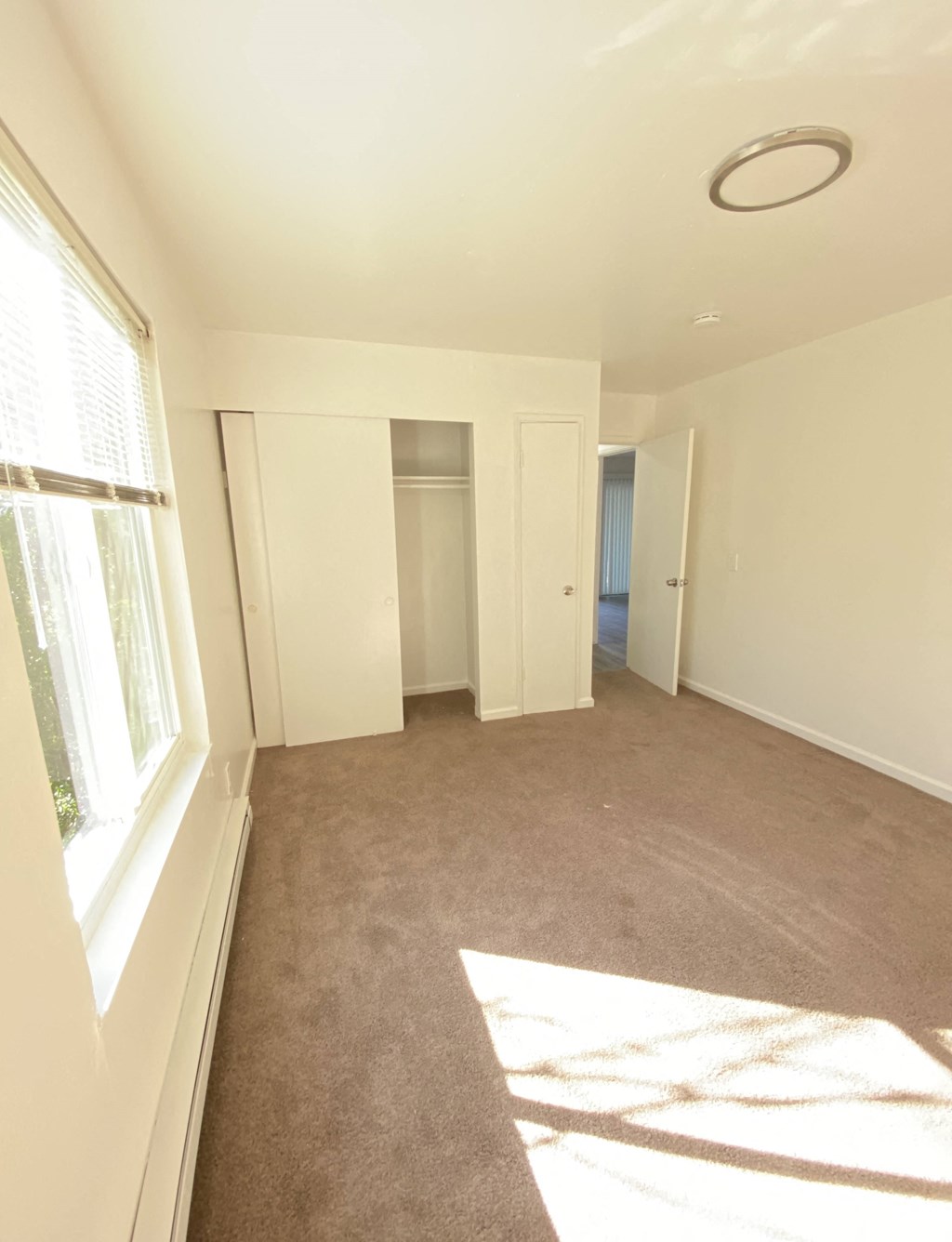 an empty living room with a large window and a closet