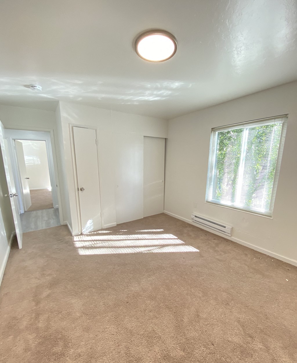 an empty living room with a large window and carpet