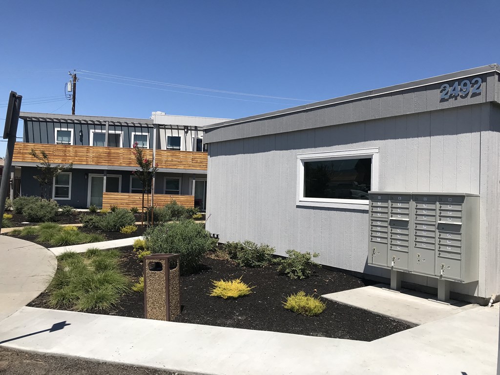 a gray building with a wooden building in the background