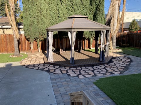 A gazebo is surrounded by a circular brick patio.