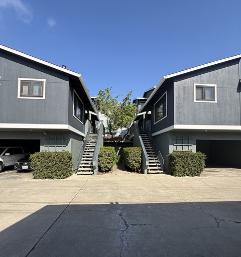 Two houses with grey exteriors and staircases leading to the second floor.