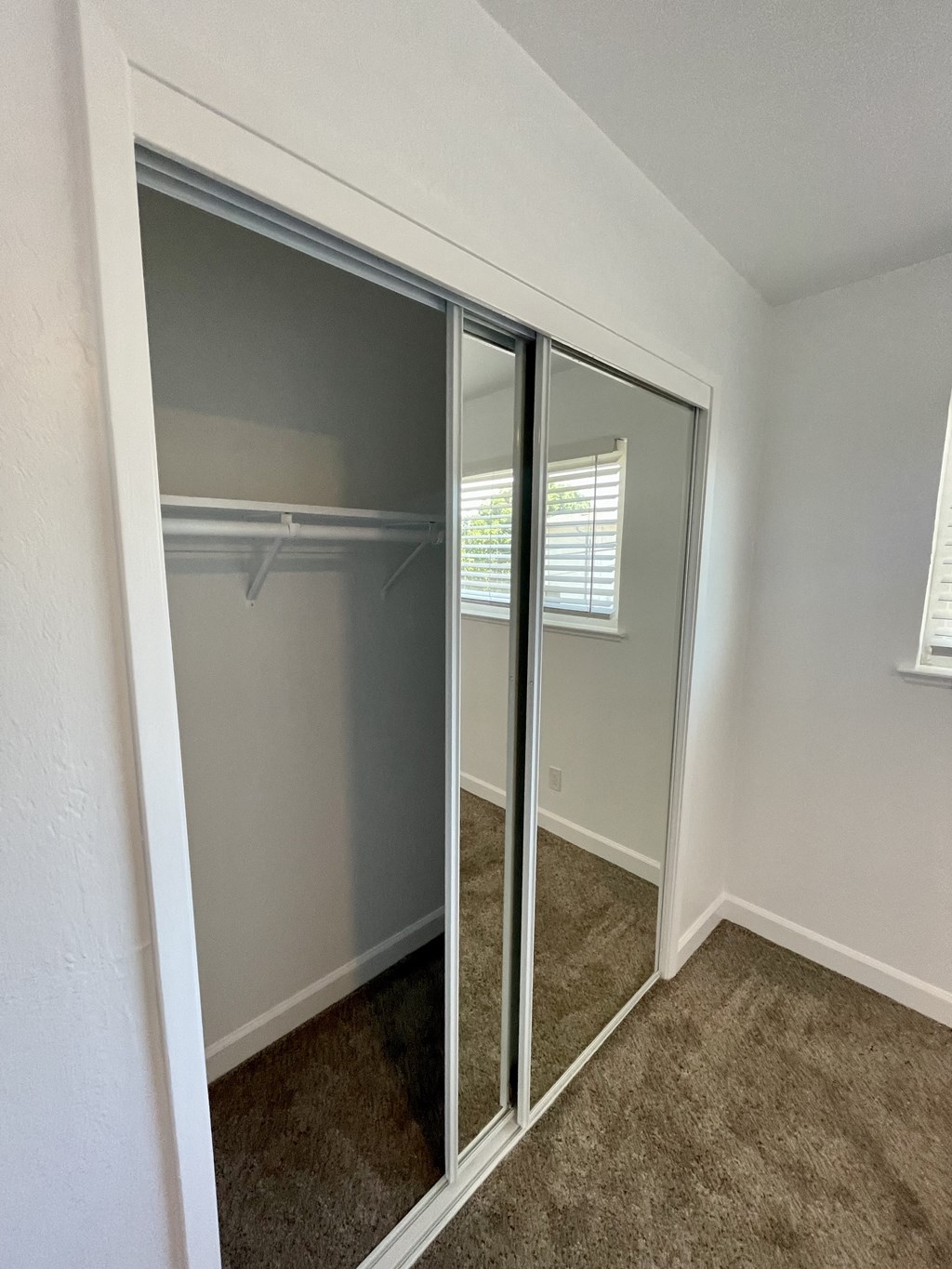 an empty bedroom with mirrored closet doors