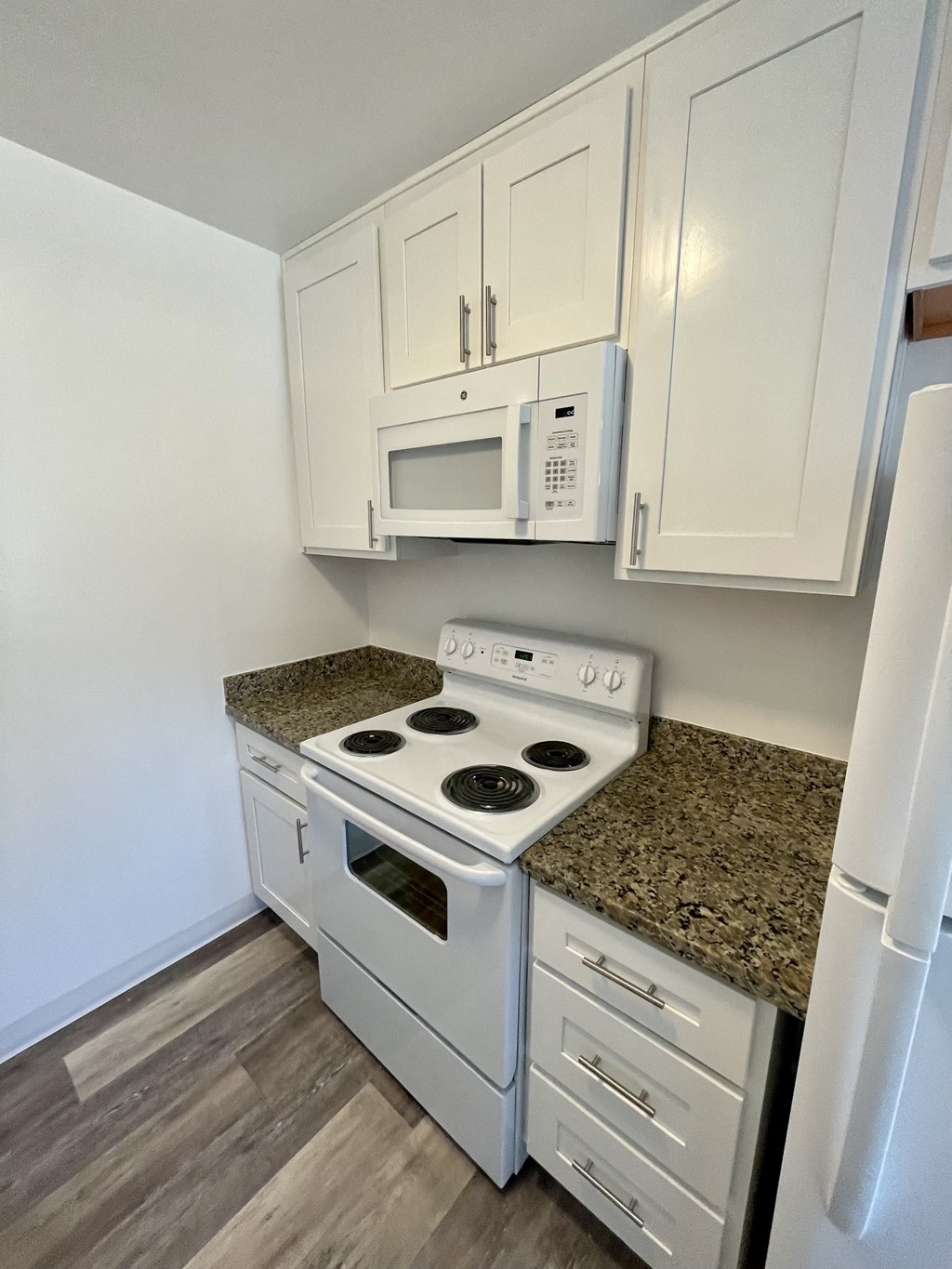 an empty kitchen with white appliances and white cabinets