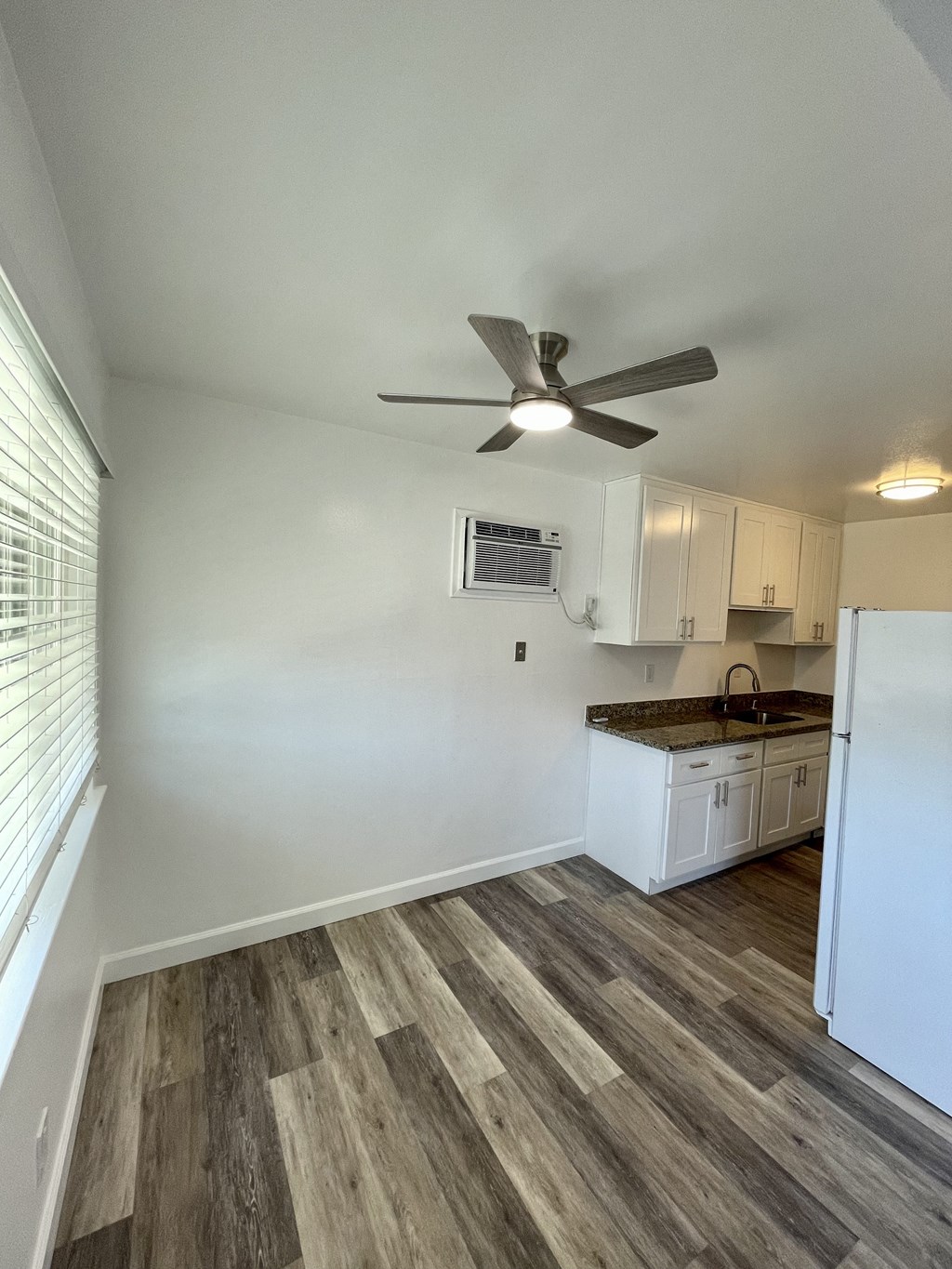 an empty kitchen with white cabinets and a ceiling fan