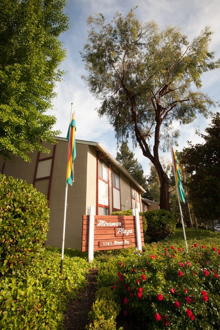 a building with a wooden sign and flags in front of it
