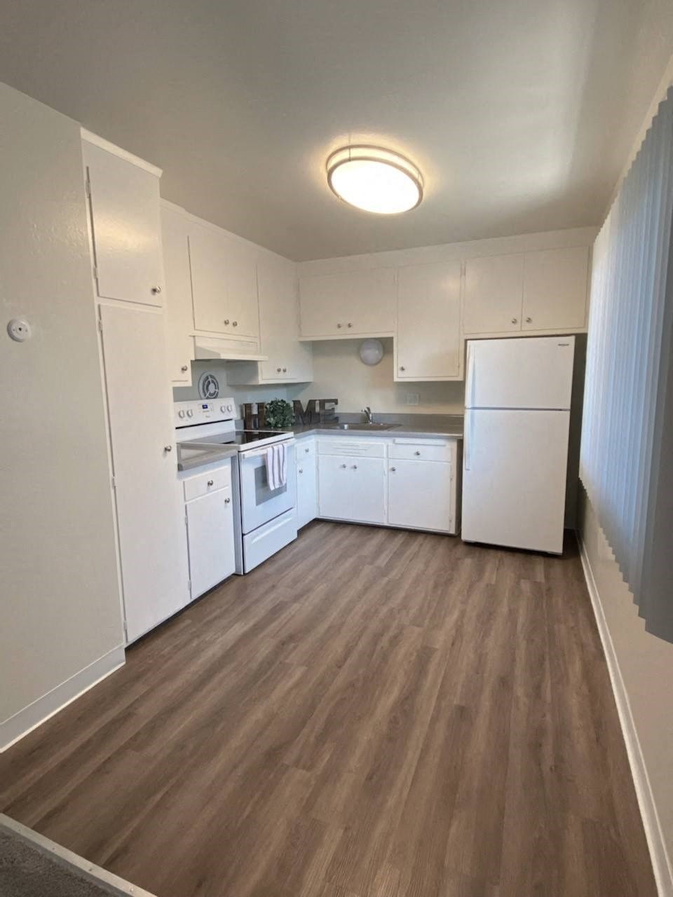a kitchen with white cabinets and a wood floor