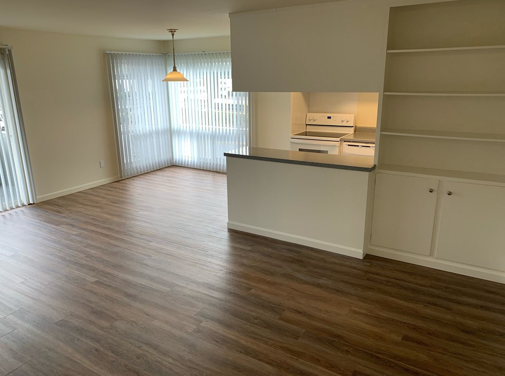 an empty kitchen and living room with wood flooring
