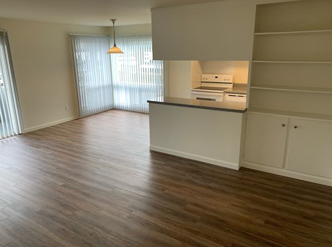 an empty kitchen and living room with wood flooring