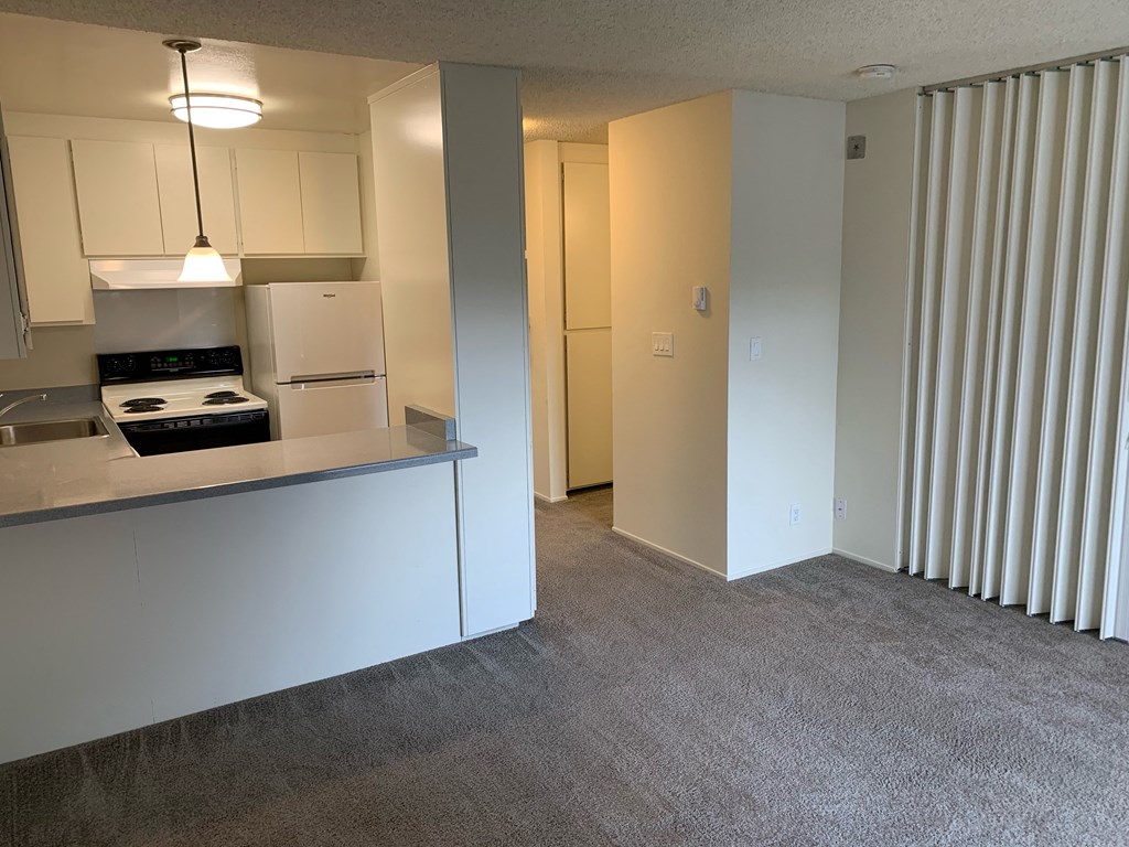 a kitchen and a living room with white cabinets and a window