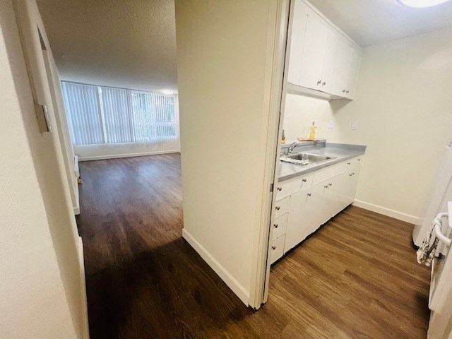 an empty kitchen with white cabinets and a wood floor