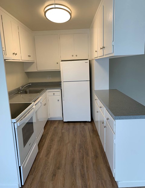 an empty kitchen with white cabinets and a white refrigerator