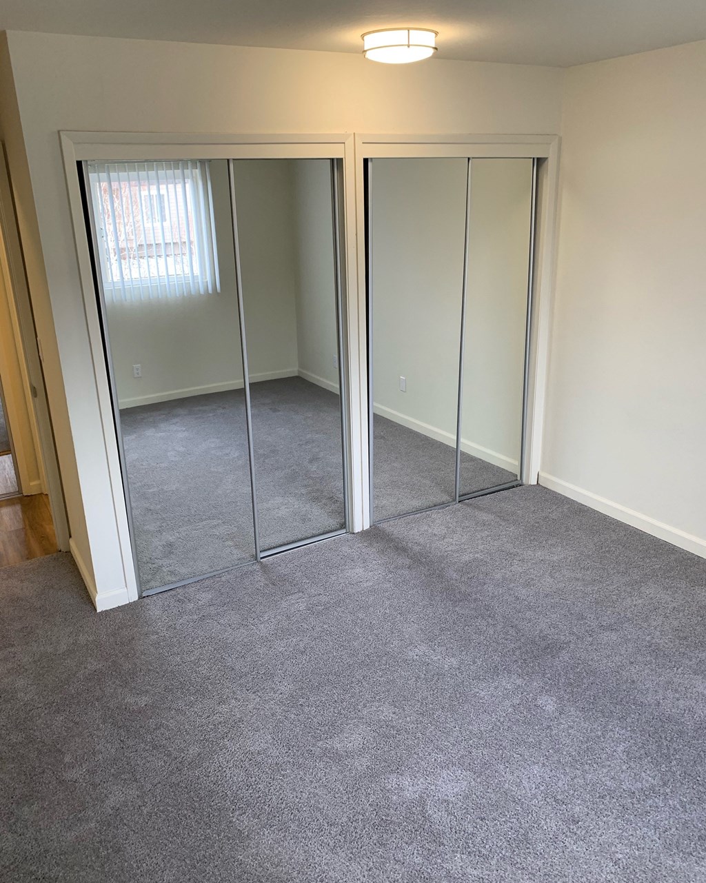 a carpeted room with three mirrored closet doors