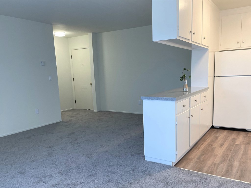 a kitchen with white cabinets and a counter top in a empty room