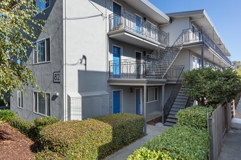 an apartment building with stairs and balconies and a sidewalk