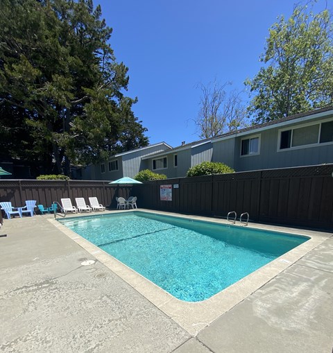 a swimming pool with chairs and a fence around it