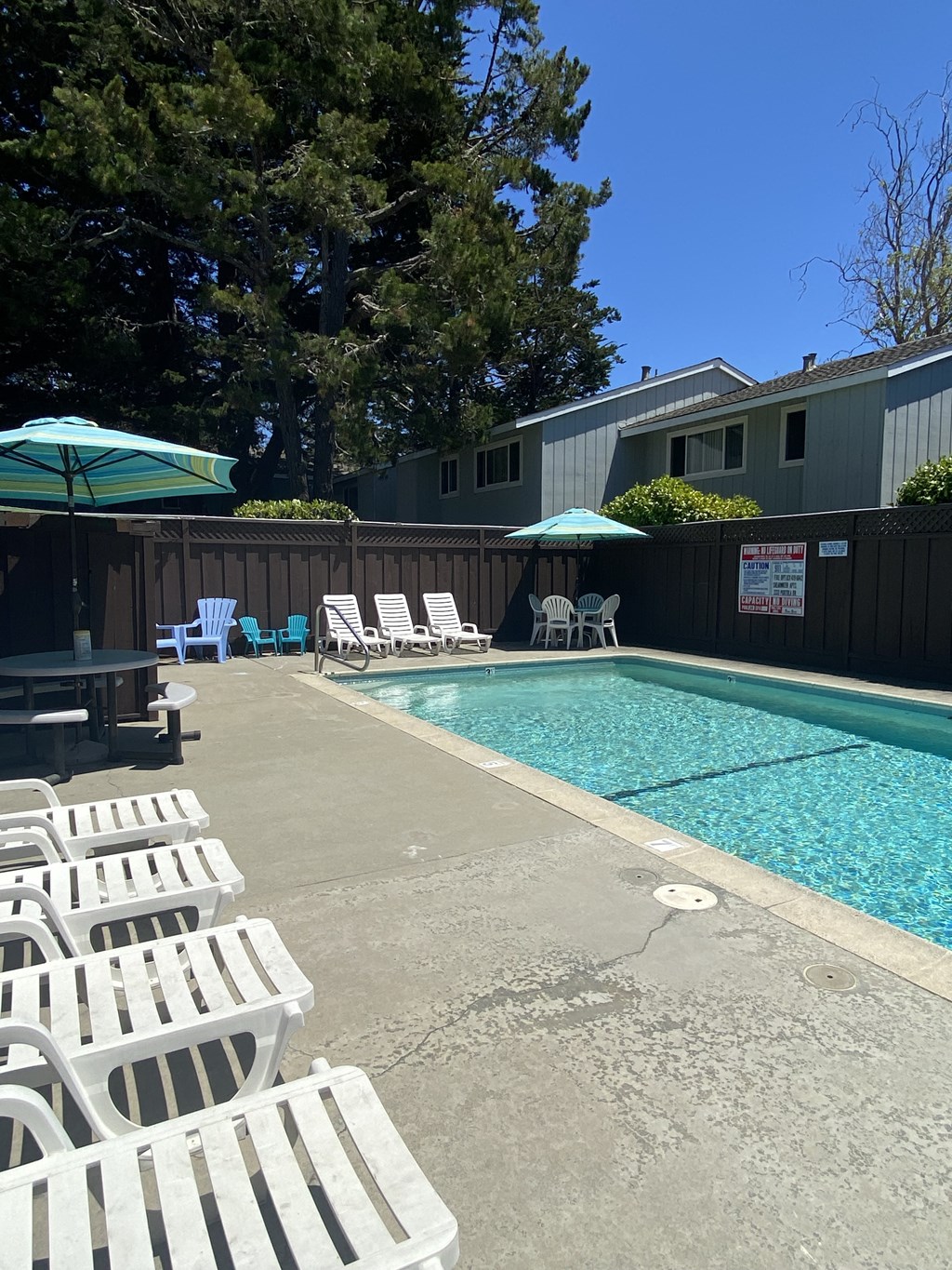 a pool with white chairs and umbrellas and a building in the background