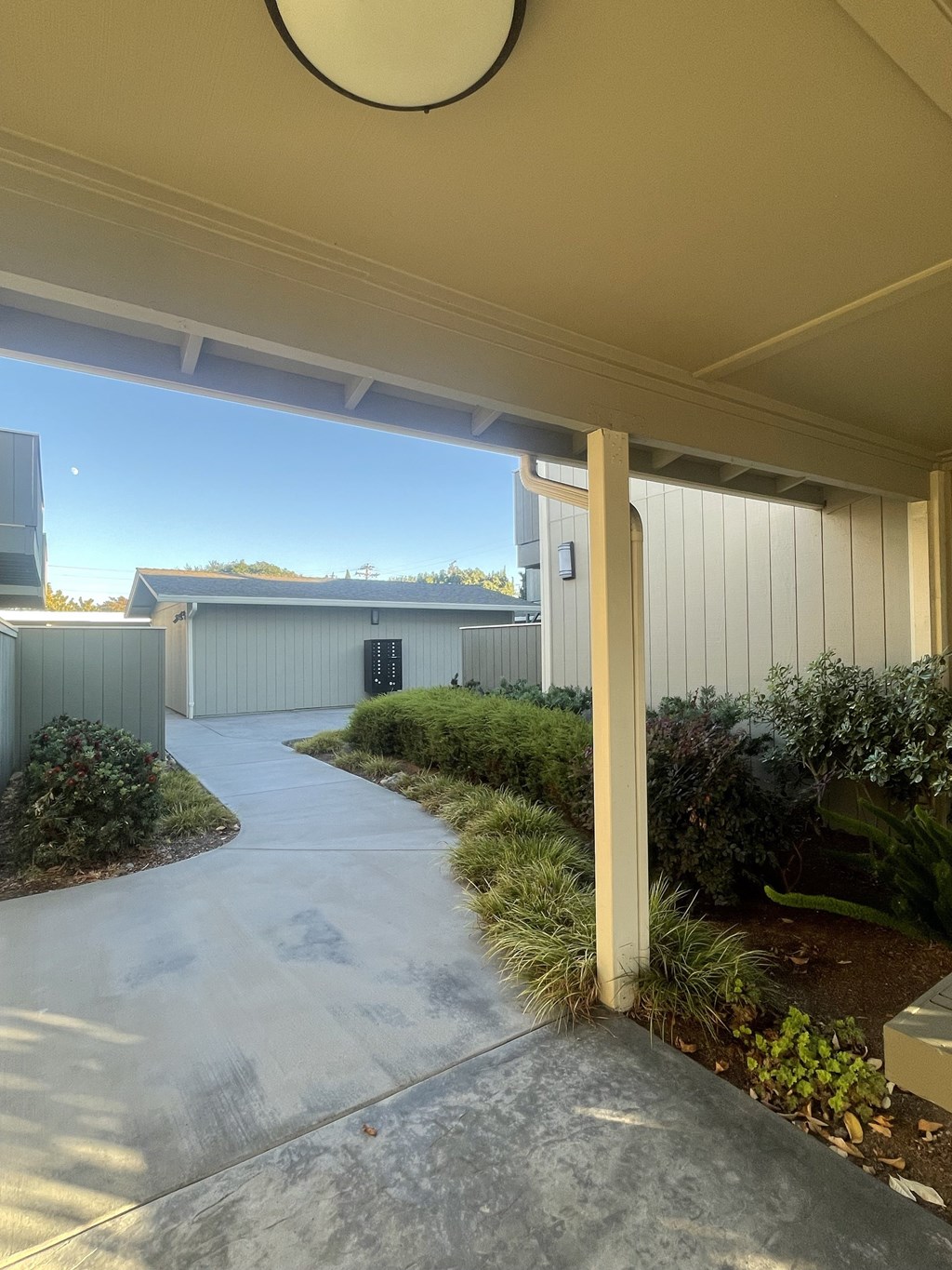 A concrete pathway leads to a building with a metal roof.