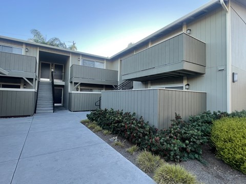 A concrete building with a grey facade and a small garden in front.