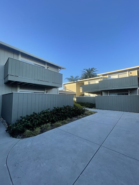 A modern building with a grey exterior and a clear blue sky in the background.