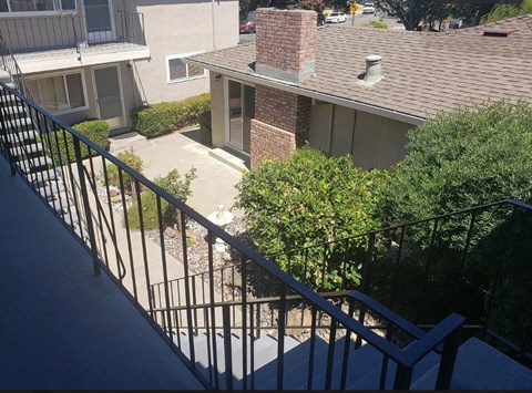 A balcony with a black railing and a view of a residential area.