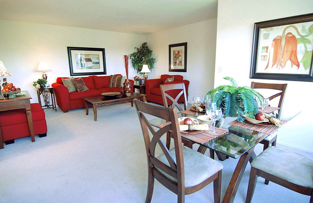 A living room with red couches, a brown wood dining set with four chairs and a wall art the living room of a unit of a Prodesse Property Group 1211 Garbo Way  San Jose, CA 95117