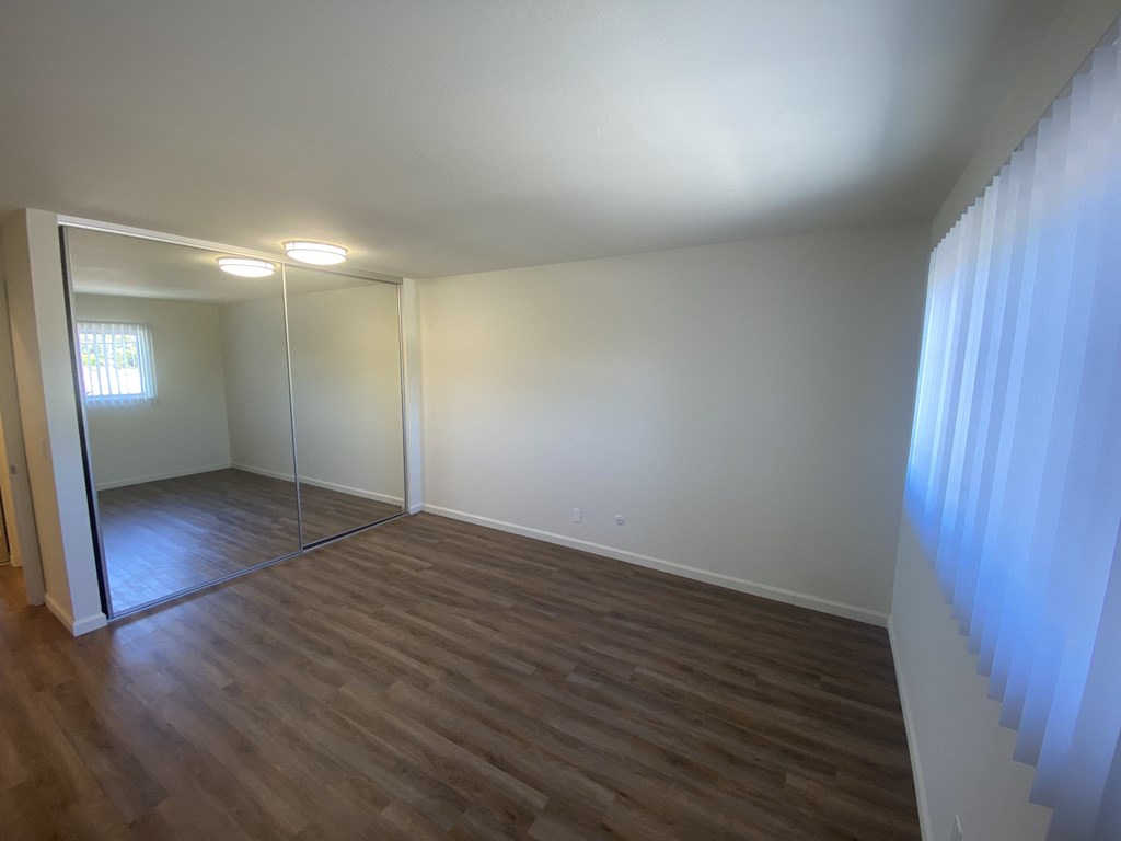 an empty living room with wood flooring and a mirror