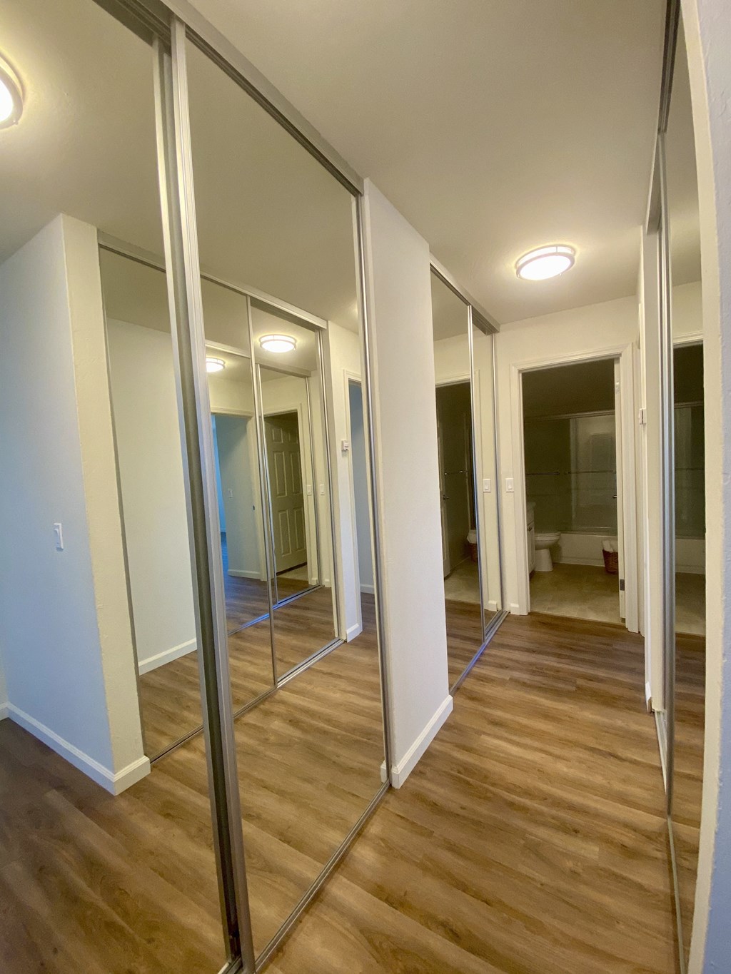 a walk in closet with mirrors on the wall and a wooden floor