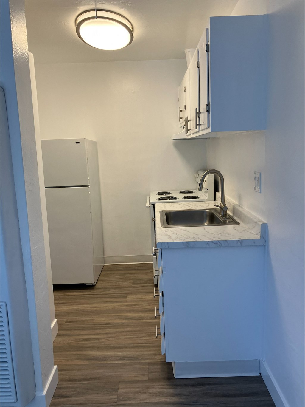 an empty kitchen with a sink and a refrigerator