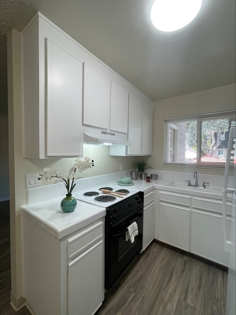 A kitchen with white cabinets and a black stove top.