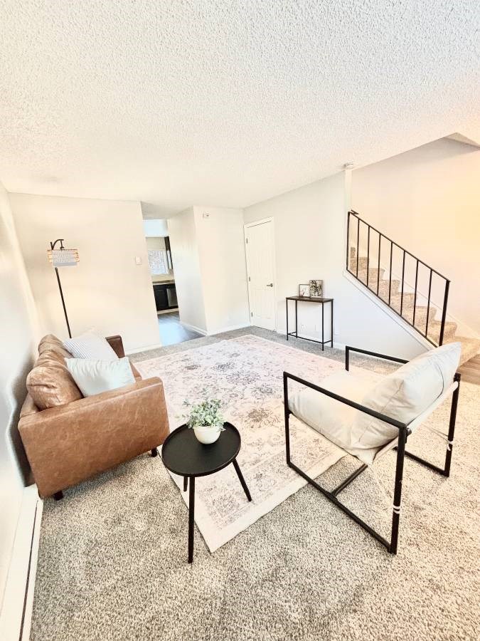 Campbell Plaza Apartments
710 Nido Drive, Campbell, CA 95008. A living room with a brown couch, a white chair, and a small table with a plant on it.