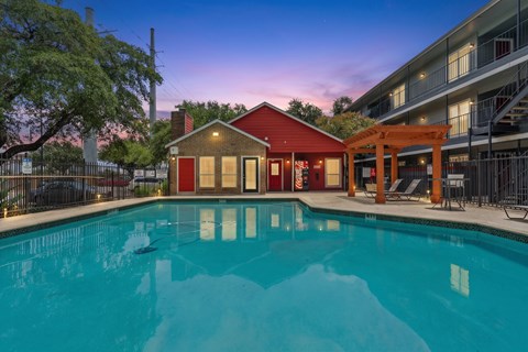 A pool in front of a red building with a gazebo in the background.