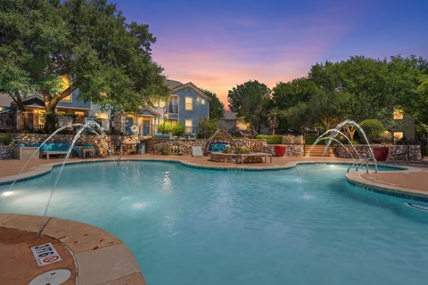 A large swimming pool surrounded by a fence and trees.