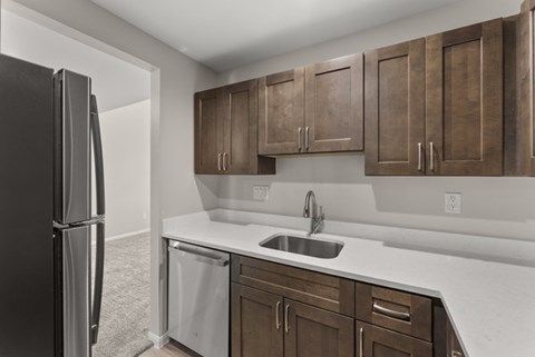 A kitchen with brown cabinets and a black refrigerator.