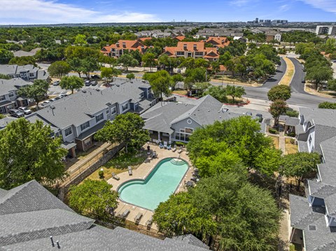 A bird's eye view of a residential area with houses and a swimming pool.