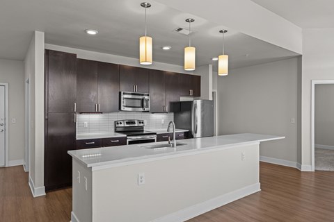 A modern kitchen with dark brown cabinets and stainless steel appliances.