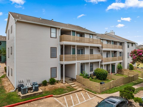 A residential building with a parking lot in front.