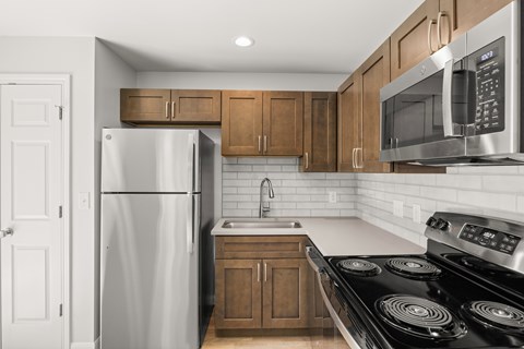 A kitchen with a stove, refrigerator, and microwave.