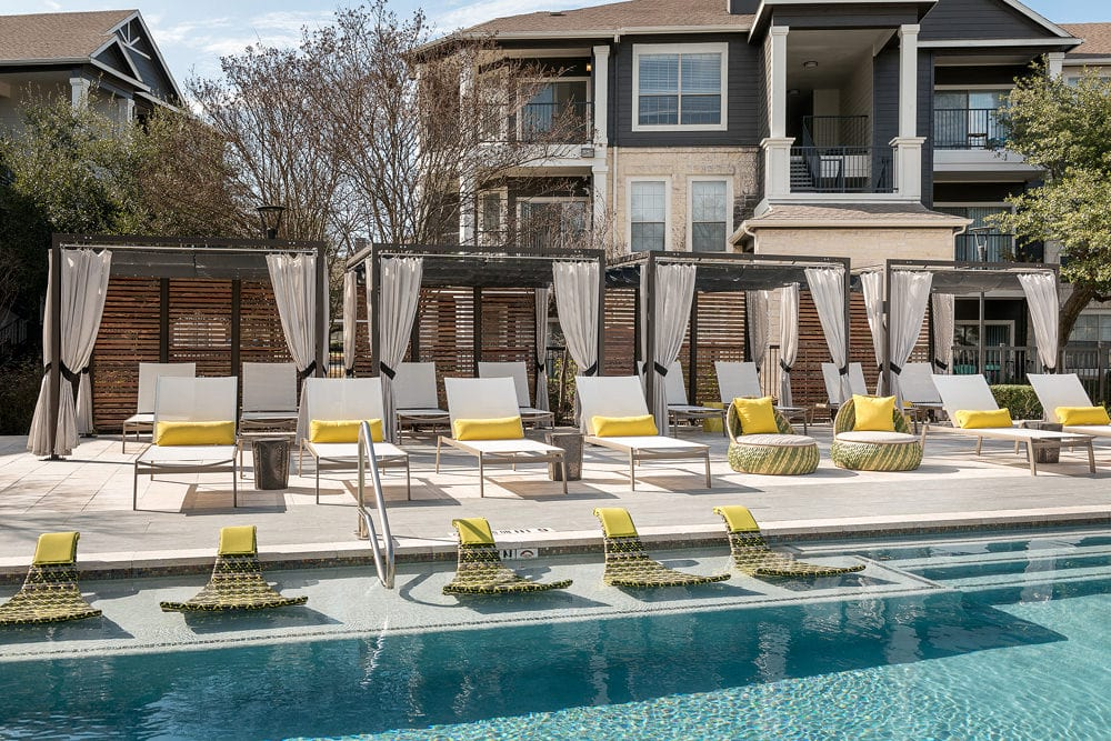 a pool with chairs and umbrellas next to a house