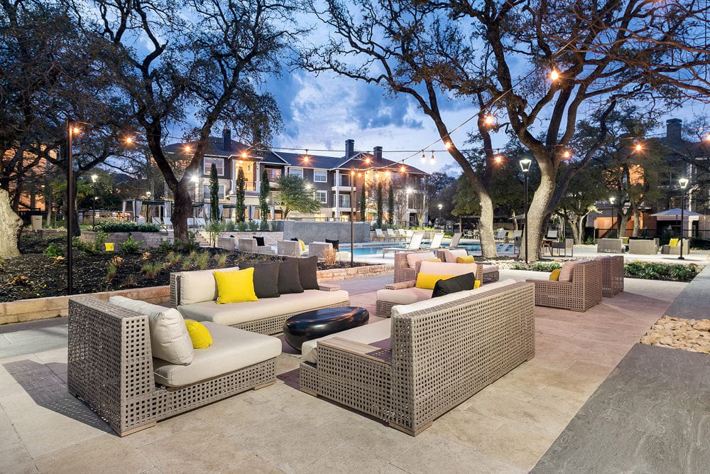 a patio with furniture and a pool at night