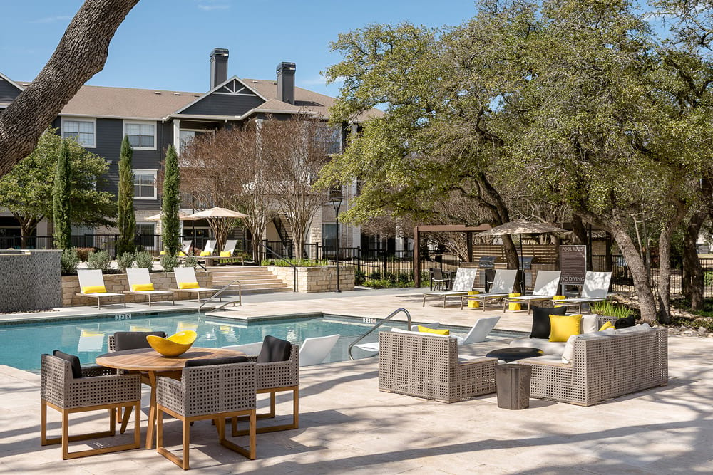 a swimming pool with tables and chairs near a hotel