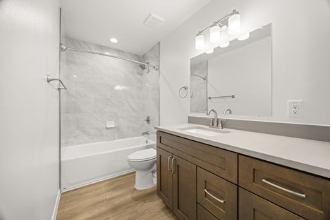 A modern bathroom with a white toilet, wooden cabinets, and a walk-in shower.
