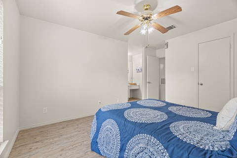 A bedroom with a bed and a ceiling fan.