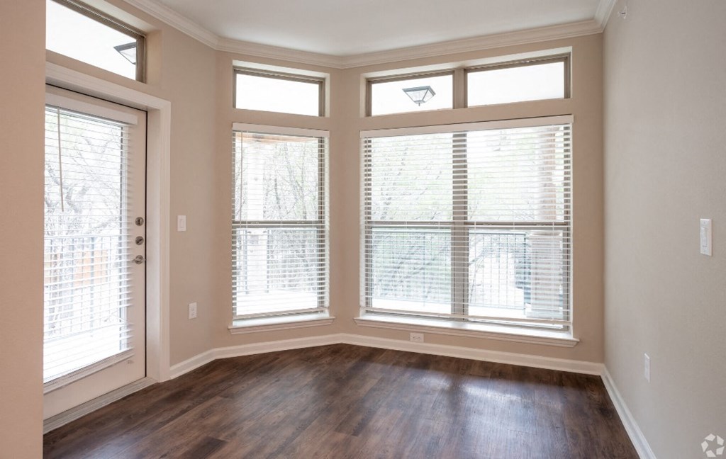 an empty living room with large windows and wood floors
