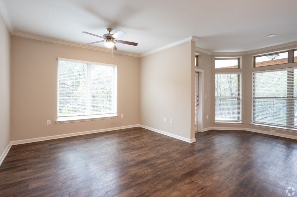 an empty living room with wood floors and a ceiling fan