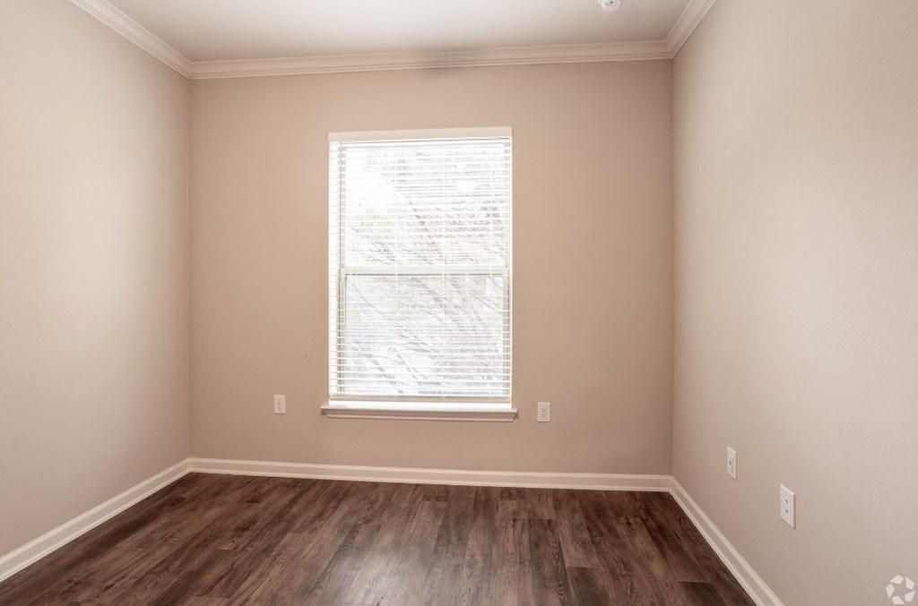 an empty room with wooden floors and a window